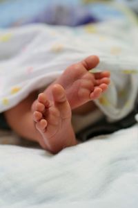 Low section of baby resting on bed