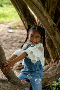 Smiling girl sitting on tree trunk