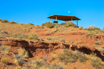 Lifeguard hut on field against clear blue sky