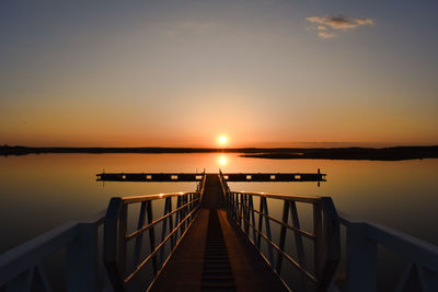 Pier over lake against sky during sunset