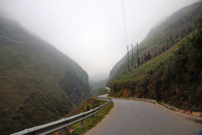 Empty road by mountains against sky