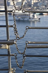 Close-up of chain on railing against sea