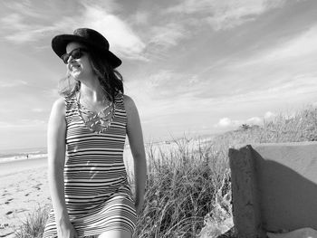 Smiling woman standing at beach against sky