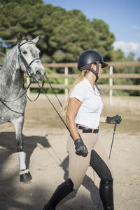 Side view of woman with horse walking in ranch