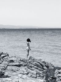 Full length of woman on rock at beach against sky