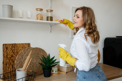 Beautiful girl wipes the shelves in the kitchen