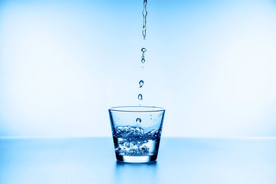 Close-up of water drop on glass against blue background