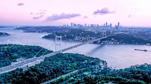High angle view of bridge and cityscape against cloudy sky