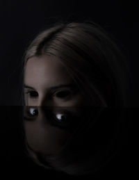 Close-up portrait of teenage girl against black background