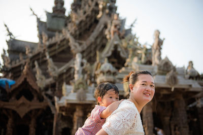 Portrait of mother and daughter against sky