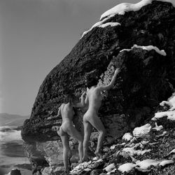 Woman standing on rock by sea against sky