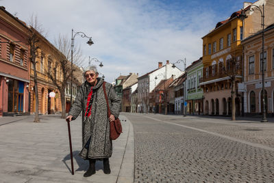 Portrait of man standing on street against buildings in city