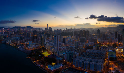 Aerial view of illuminated city buildings against sky at sunset