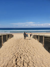 Rear view of men on beach against sky