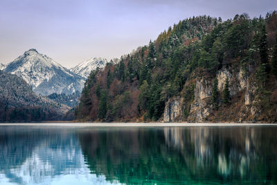 Trees and mountain reflecting on calm lake during winter