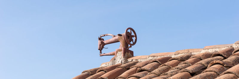 Low angle view of man on rock against clear blue sky