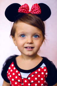 Happy baby girl in the studio in a red dress with mickey mouse ears and mouse