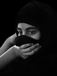 Portrait of young woman holding covering face