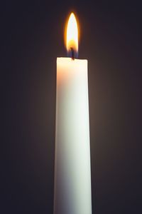 Close-up of lit candle in darkroom