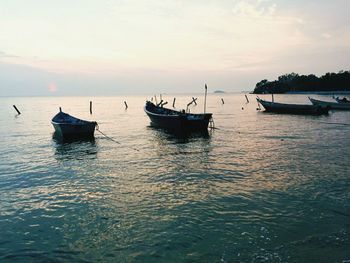 Boats in sea against sky during sunset