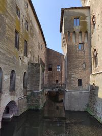 Old building by canal against clear sky