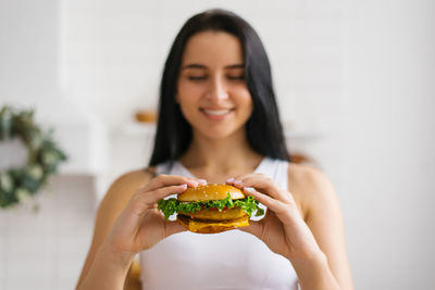 Portrait of young woman holding burger