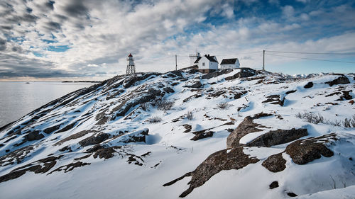 Scenic view of lighthouse on snow mountain against cloudy sky