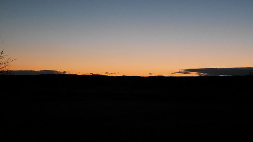 Silhouette landscape against clear sky during sunset