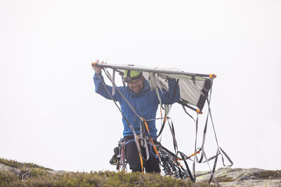 Rock climber carries portaledge above head.