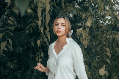 Portrait of young woman standing against plants