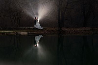 Woman standing by bare trees in forest