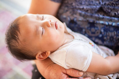 Close-up of baby girl lying on bed