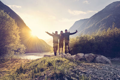 Rear view of people standing on rock against sky