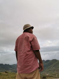 Rear view of man standing on mountain against sky