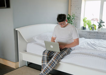 Young woman using digital tablet while lying on bed at home