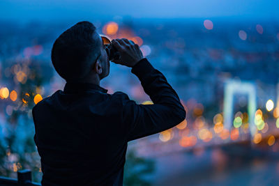 Rear view of man having drink at dusk