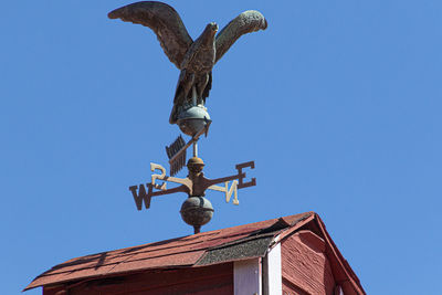 Low angle view of statue on roof against clear sky