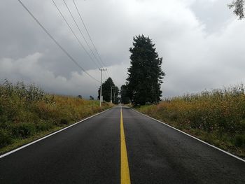 Road by trees against sky