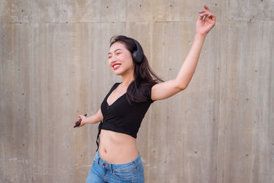 Side view of a smiling young woman standing against wall