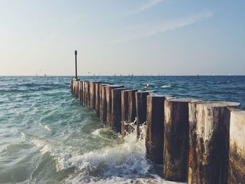 Wooden posts in sea against sky