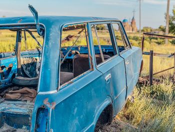 Abandoned car on land against sky