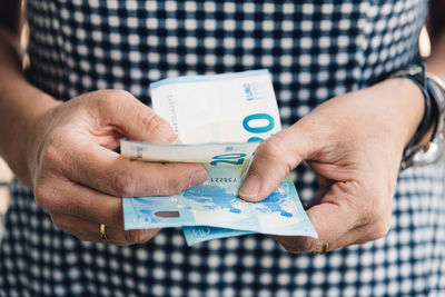 Midsection of woman holding paper currency