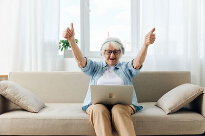 Young woman using laptop while sitting on sofa at home