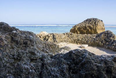 Rocks on beach against clear sky