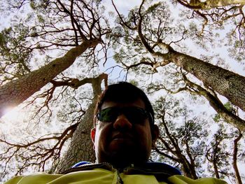 Low angle view of boy and tree against sky