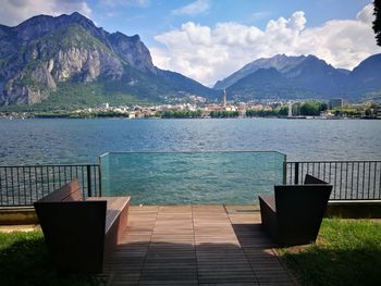 Chairs by swimming pool against lake and mountains