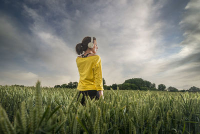 Rear view of woman standing on field against sky