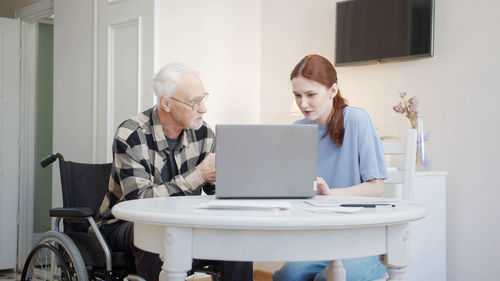 Side view of woman using laptop at home