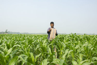 Indian farmer holding water pipe at corn field