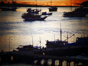 Boats moored at harbor during sunset